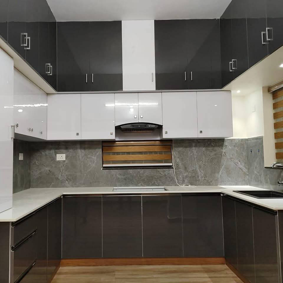Spacious open kitchen with marble countertop and wooden finish at Marthandam, Tamil Nadu